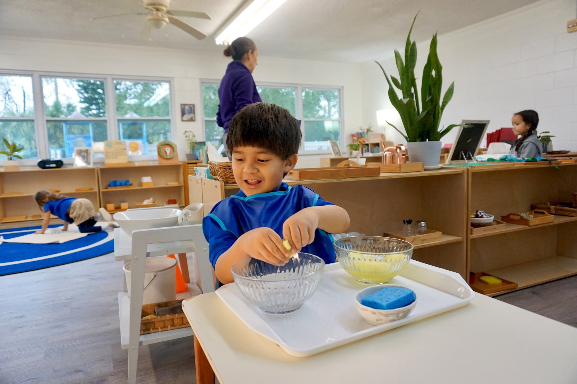 Montessori toddler classroom with young children engaging in hands-on activities and exploration.